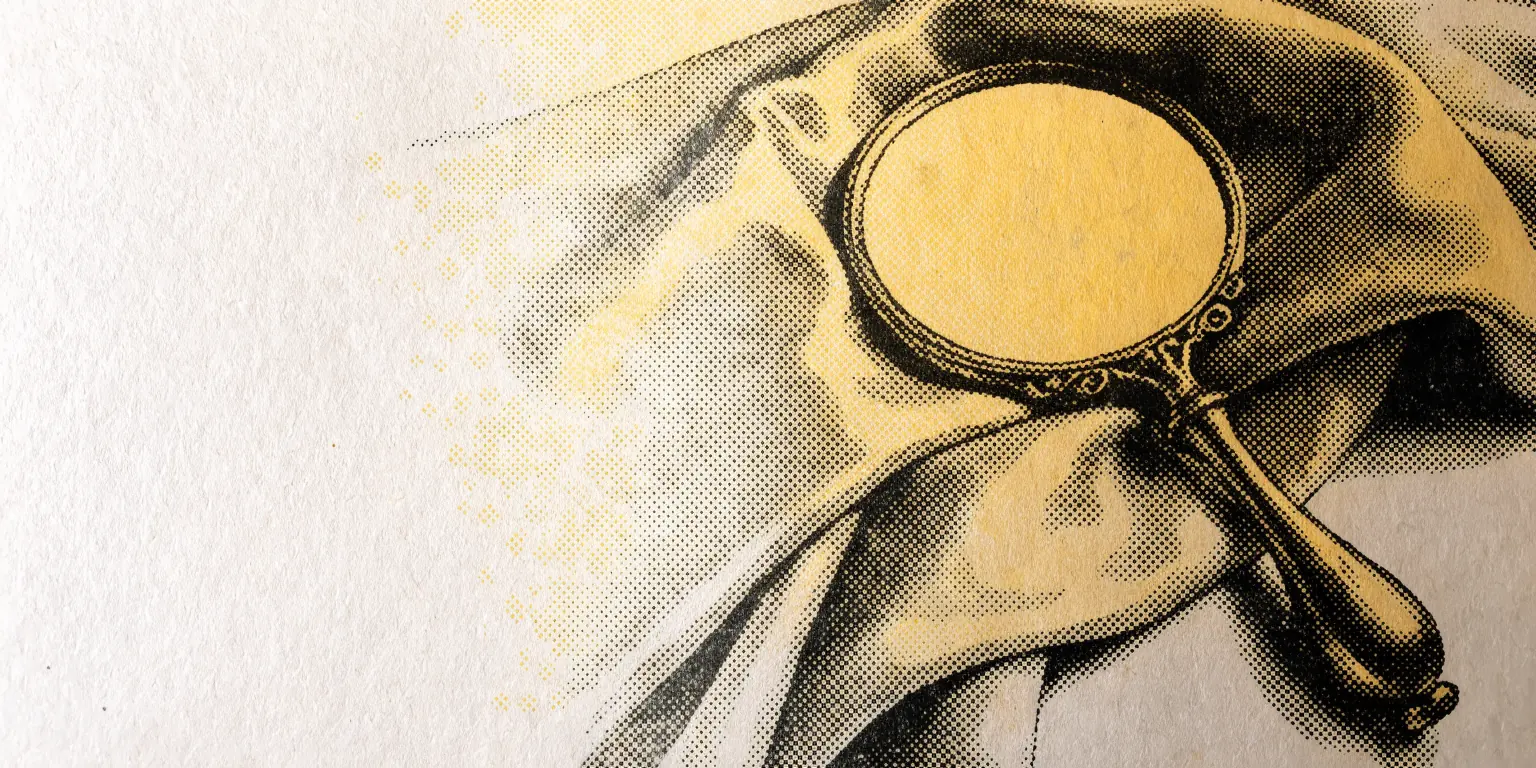 A single vintage brass hand mirror lying on a folded silk scarf, nothing else
