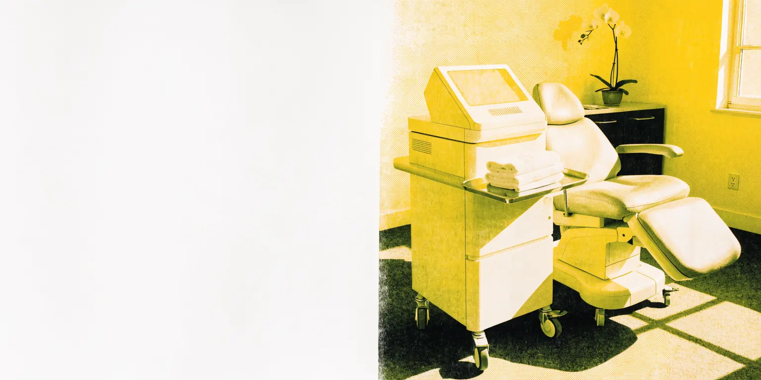 A quiet, sunlit aesthetic treatment room with a cream fractional laser console on wheels beside an empty, clearly reclining treatment chair, fresh white towels folded on a small steel tray, and a potted orchid on the counter.