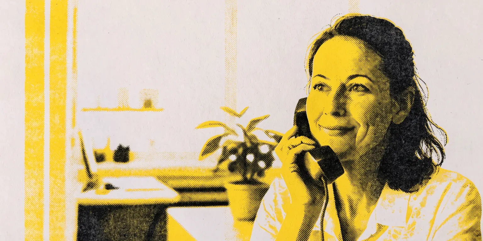 A relaxed, polished woman in her forties, framed from the chest up, sits in a bright aesthetic practice reception area, smiling softly while holding a phone loosely, a small plant and a blurred front desk behind her.