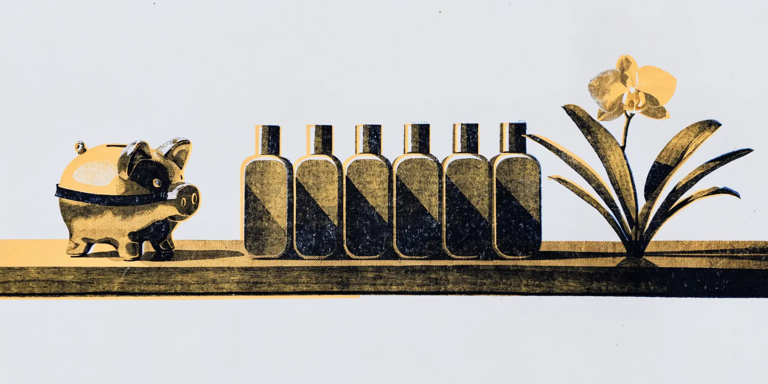 A small gold piggy bank wearing a tiny sash on a walnut shelf beside a row of plain skincare bottles and an orchid.